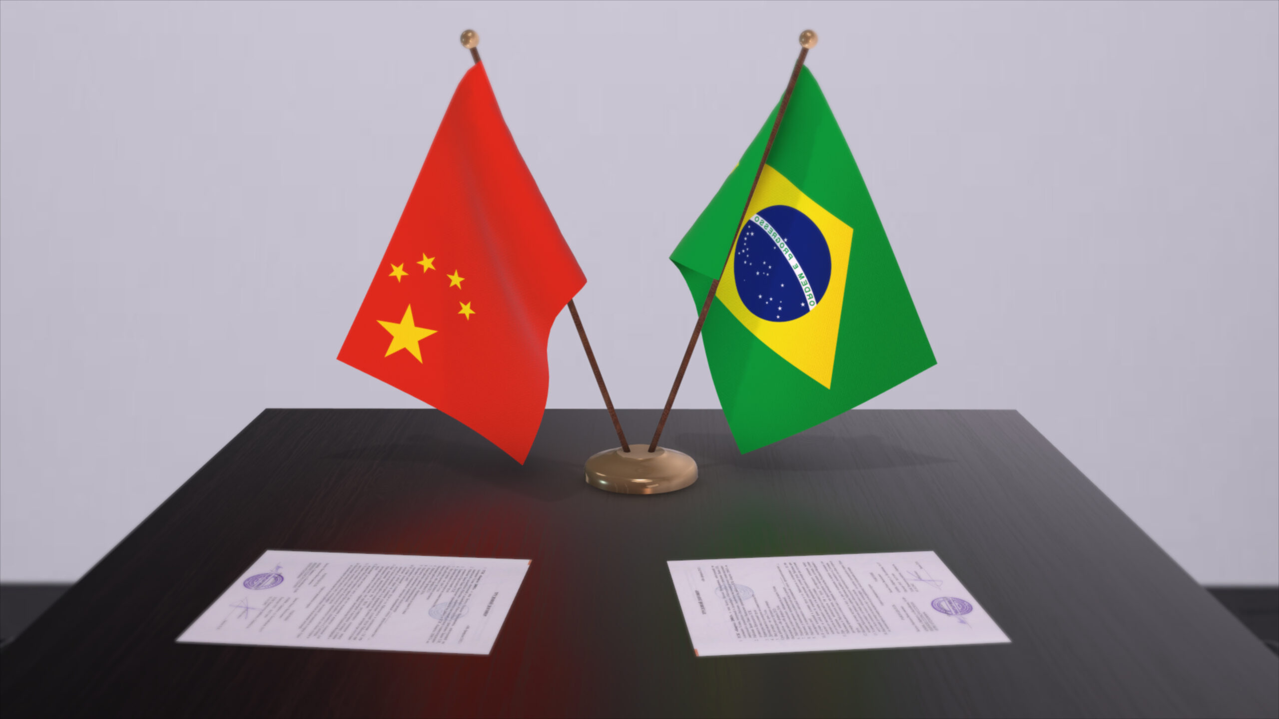 Bandeiras da China e do Brasil apoiadas em cima de uma mesa, simbolizando a relação diplomática entre os países.
